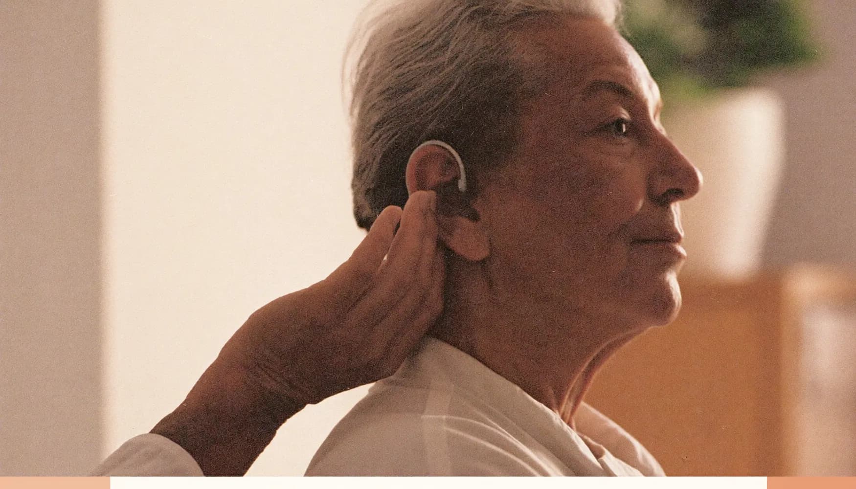 Une personne âgée de profil, la main effleurant son oreille, apaisée.